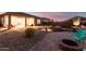 Gorgeous backyard with a firepit, custom patio, and mountain views at twilight at 8773 S 167Th Dr, Goodyear, AZ 85338