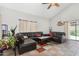 Spacious living room featuring vaulted ceiling, tile floors, a ceiling fan, and a comfortable leather sectional sofa at 11101 N 82Nd Dr, Peoria, AZ 85345