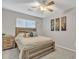 Inviting bedroom features a bed, nightstand, wood-look ceiling fan and a window with blinds for natural light and privacy at 1145 E Silktassel Trl, San Tan Valley, AZ 85143