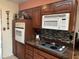 Kitchen featuring cooktop, oven, microwave, and warm wood cabinets with tile backsplash at 12236 N Pebble Beach Dr, Sun City, AZ 85351