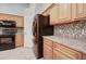 Well-equipped kitchen with black appliances, wooden cabinets, and tiled backsplash, making it ideal for cooking at 12326 N Lang Rd, Florence, AZ 85132