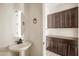 Powder room featuring a pedestal sink and dark wood cabinets at 16074 W Cortez St, Surprise, AZ 85379