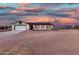 Charming single-story home with a two-car garage and rustic wooden fence under colorful sunset skies at 20438 W Carver Rd, Buckeye, AZ 85326