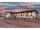 Quaint single-story home with a rustic wooden fence and two-car garage under a colorful sunset sky at 20438 W Carver Rd, Buckeye, AZ 85326