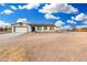 Single-story home with a two-car garage and rustic wood fence under a blue and cloudy sky at 20438 W Carver Rd, Buckeye, AZ 85326