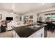 Open-concept kitchen with white cabinets, an island with seating, and a seamless flow into the living and dining areas at 20438 W Carver Rd, Buckeye, AZ 85326