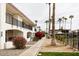 Exterior view of condos featuring balconies and desert landscaping with mature palm trees at 240 S Old Litchfield Rd # 206, Litchfield Park, AZ 85340