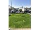 Exterior view of condo community featuring lush green grass and lots of palm trees at 240 S Old Litchfield Rd # 208, Litchfield Park, AZ 85340