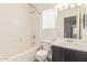 A white-tiled bathroom with a combination tub and shower and a dark vanity at 2551 E Kent Ave, Gilbert, AZ 85296