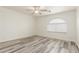 Bright bedroom features a ceiling fan, wood-look flooring, a large window, and neutral paint at 2551 E Kent Ave, Gilbert, AZ 85296