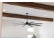 Detailed view of a modern, black ceiling fan with wood beam ceiling accents at 29348 N Clear Ridge Rd, Rio Verde, AZ 85263