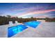 Relaxing pool and spa area with lounge chairs and an outdoor kitchen under a colorful sky at 29348 N Clear Ridge Rd, Rio Verde, AZ 85263