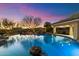 Beautiful pool at dusk, featuring natural rock details and mature landscaping at 37080 N 109Th Way, Scottsdale, AZ 85262