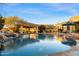 Lush backyard with a stunning pool featuring rock accents, a covered pavilion, and clear blue water at 37080 N 109Th Way, Scottsdale, AZ 85262