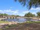 A tranquil view of the community pond, with a spillway and rocky landscaping along the shoreline at 37093 W La Paz St, Maricopa, AZ 85138