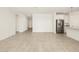 Open-concept living room with tile flooring, a stainless steel fridge and modern white cabinets at 37093 W La Paz St, Maricopa, AZ 85138