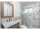 Updated bathroom featuring a marble countertop, framed mirror, and decorative tile and glass shower at 4307 E Turney Ave, Phoenix, AZ 85018