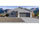 Charming single-story home with a gray exterior, a two-car garage, and a low-maintenance desert landscape in front at 5573 E Rock Bush Ln, San Tan Valley, AZ 85140