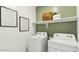 Modern laundry room with white washer and dryer and framed signs at 5573 E Rock Bush Ln, San Tan Valley, AZ 85140