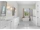 A bright bathroom features a double vanity, soaking tub, and a glass-enclosed shower with marble tiling at 56 S Prairie Rd, Gilbert, AZ 85296