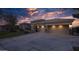 Home exterior at dusk featuring stone accents, a well-manicured lawn, and a spacious three-car garage at 56 S Prairie Rd, Gilbert, AZ 85296