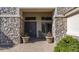 Stone accented entry way with double doors, potted plants, and covered seating area at 56 S Prairie Rd, Gilbert, AZ 85296