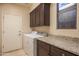 The laundry room features a full-sized washer and dryer, with dark cabinetry and granite countertops at 6993 E Soaring Eagle Way, Scottsdale, AZ 85266