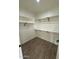 A walk-in closet with wood-look flooring has white walls and shelving and black hardware at 10281 W Concordia Dr, Arizona City, AZ 85123