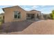 Backyard featuring gravel, lush desert landscaping, and a covered patio with fireplace at 10778 W Whitehorn Way, Peoria, AZ 85383