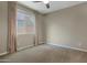 Cozy bedroom featuring carpet flooring, neutral paint, a ceiling fan, and a window with drapery for natural light at 10778 W Whitehorn Way, Peoria, AZ 85383