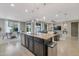 Modern kitchen with a granite-topped island overlooks a dining area and living room, creating a seamless open-concept living space at 10778 W Whitehorn Way, Peoria, AZ 85383