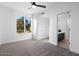 Bright bedroom featuring neutral carpet, a ceiling fan, and a large window providing ample natural light at 1157 N Date Palm Dr, Gilbert, AZ 85234