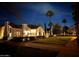 Charming home with a red tile roof, complemented by illuminated landscaping and a brick driveway under the night sky at 1307 W Palm Ln, Phoenix, AZ 85007