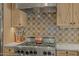 Close up of gas cooktop, designer backsplash, and custom wood cabinetry in renovated kitchen at 1307 W Palm Ln, Phoenix, AZ 85007