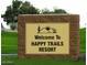 Welcome sign to Happy Trails Resort, nestled among lush lawns and desert landscaping, near Phoenix, Arizona at 17200 W Bell Rd # 26, Surprise, AZ 85374