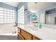 A bathroom vanity featuring bright light fixtures, wood cabinets, and a tub in the background at 1865 E Pinto Dr, Gilbert, AZ 85296