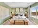 Cozy bedroom featuring green walls, neutral decor, a wicker trunk, and ample natural light at 25083 N 174Th Ln, Surprise, AZ 85387