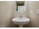 Powder room featuring neutral walls, a pedestal sink and a round mirror at 3911 S 79Th Ln, Phoenix, AZ 85043