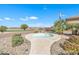 A tranquil backyard featuring a circular spa, lush landscaping, and views of the nearby golf course at 3956 N San Marin Dr, Florence, AZ 85132