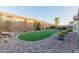 Manicured backyard featuring artificial grass, desert landscaping, mature shrubs and trees, and a stone border at 4107 N Hawthorn Dr, Florence, AZ 85132