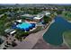 Aerial view of community amenities with a pool, spa, lake, and clubhouse amidst lush greenery at 4424 N Potomac Dr, Florence, AZ 85132