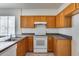 Functional kitchen with stainless steel sink, white appliances, and tile flooring at 6557 W Puget Ave, Glendale, AZ 85302