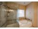 Well-lit bathroom featuring a glass-enclosed shower and a soaking tub at 6640 W Honeysuckle Dr, Phoenix, AZ 85083