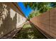 A clean side yard features artificial grass and a brick-lined pathway, framed by a tall privacy wall at 6640 W Honeysuckle Dr, Phoenix, AZ 85083