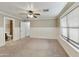 Spacious bedroom with neutral carpet, ceiling fan, natural light from the window, and an attached bathroom at 8434 E Natal Cir, Mesa, AZ 85209