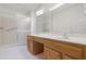 Bright bathroom featuring a large mirror, dual sinks, wood cabinets and a walk-in shower at 9214 E Diamond Dr, Sun Lakes, AZ 85248