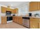 Cozy kitchen with wood cabinets, tile floors, and modern stainless steel appliances at 9214 E Diamond Dr, Sun Lakes, AZ 85248