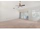 A well-lit living room with neutral carpet, sliding glass doors, and a ceiling fan at 9214 E Diamond Dr, Sun Lakes, AZ 85248