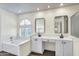 Bright bathroom featuring dual sinks, framed mirrors, white cabinets, and a bathtub under an arched window at 9652 E Ludlow Dr, Scottsdale, AZ 85260