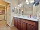 Bright bathroom featuring a double sink vanity with cherry wood cabinets and tile flooring, and a door to laundry room at 10323 W Carousel Dr, Arizona City, AZ 85123